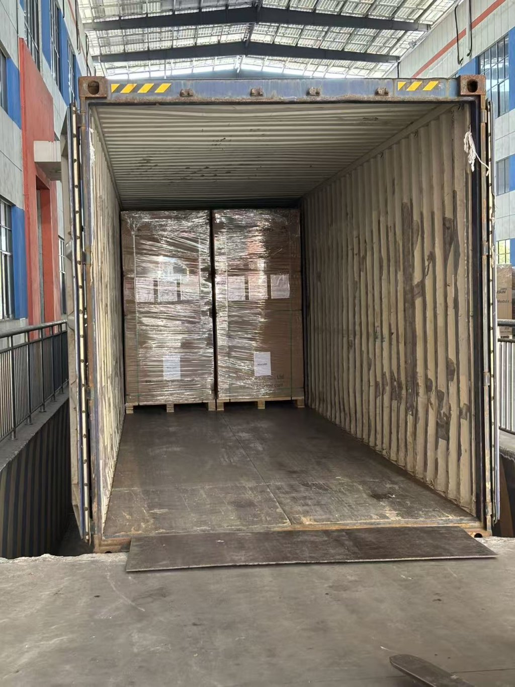 Workers loading solar module pallets into a shipping container